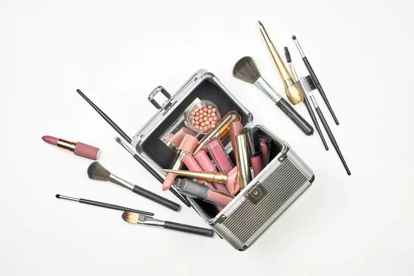 Cosmetic box with professional beauty tools and accessories on white background