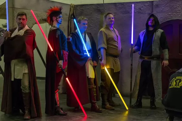 Cosplayer verkleidet als Jedi und Sith mit Lichtschwertern