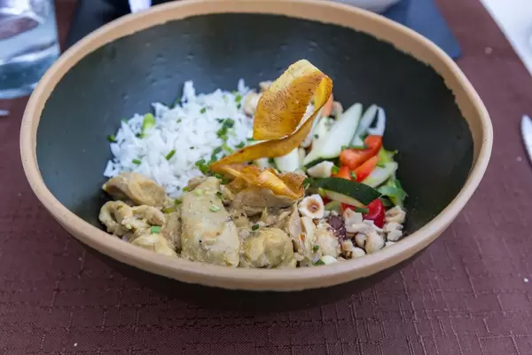 Country chicken curry Q11 style with seasonal vegetables and rice in a black bowl at Q11, Pollença