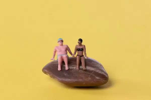 Couple in bathing suit sitting on rock
