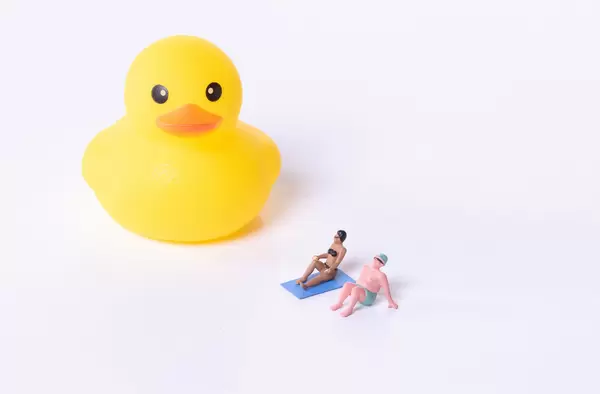 Couple in bathing suit with yellow rubber duck on white background