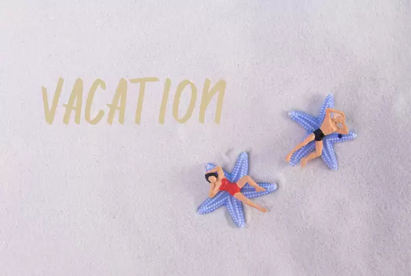 Couple relaxing at sandy beach with Vacation text