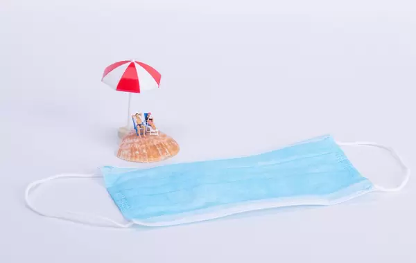 Couple sitting in deck chairs on sea shell and medical face mask