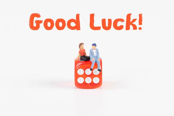 Couple sitting on a dice with Good Luck text