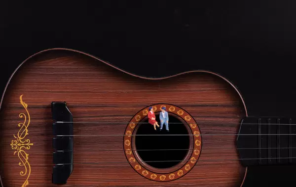 Couple sitting on a guitar with black background