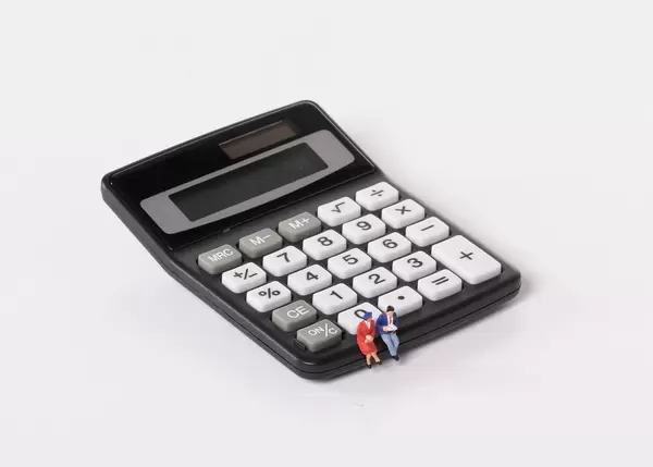 Couple sitting on calculator on white background