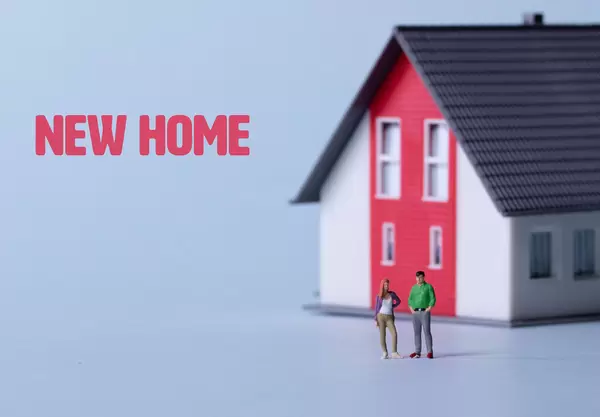 Couple standing in front of a house with New home text