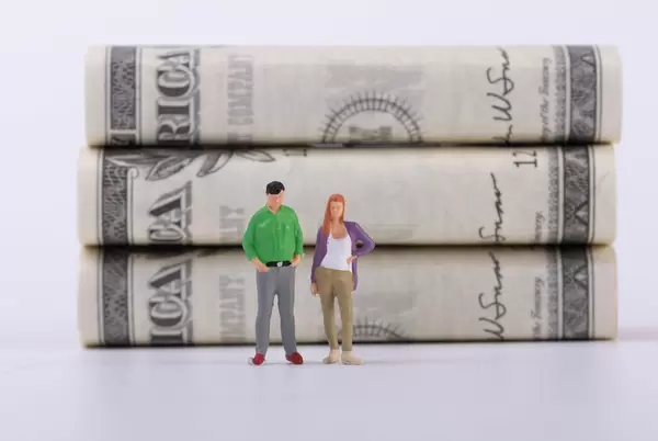 Couple standing in front of money stacks