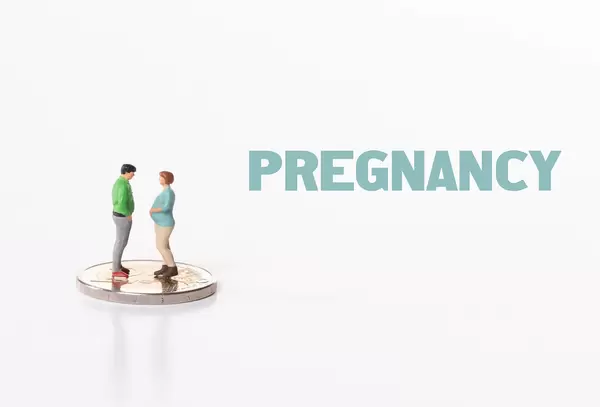 Couple standing on 2 Euro coin with Pregnancy text