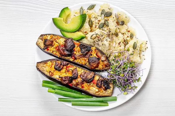 Couscous with seeds, micro greens cabbage, baked eggplant and pieces of fresh avocado and young onions on a plate (Flip 2019)