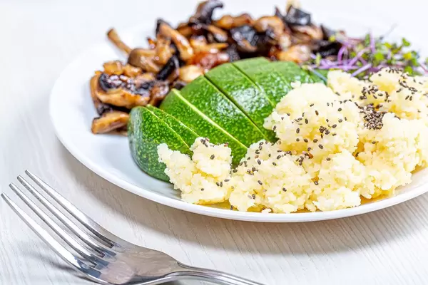 Couscousreis mit Chia-Samen, frische Avocado mit Schale, Mikrogrün-Keimsprosse und gebackenen Pilzen