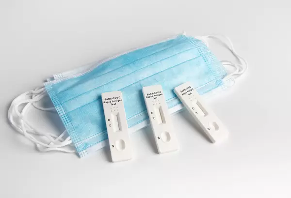 Covid-19 Antigen tests with medical face masks on white table