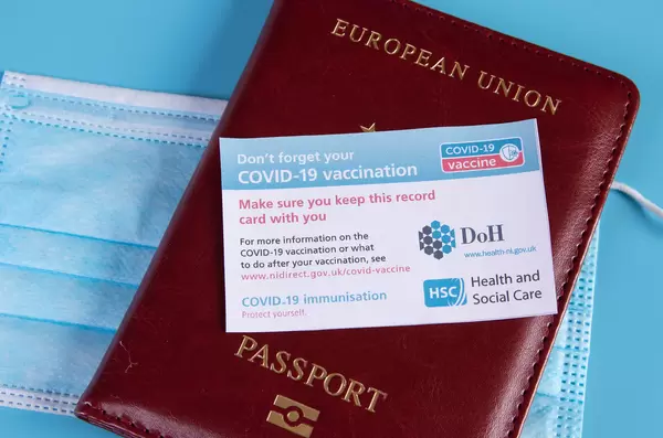Covid-19 vaccination record card with passport and medical face mask