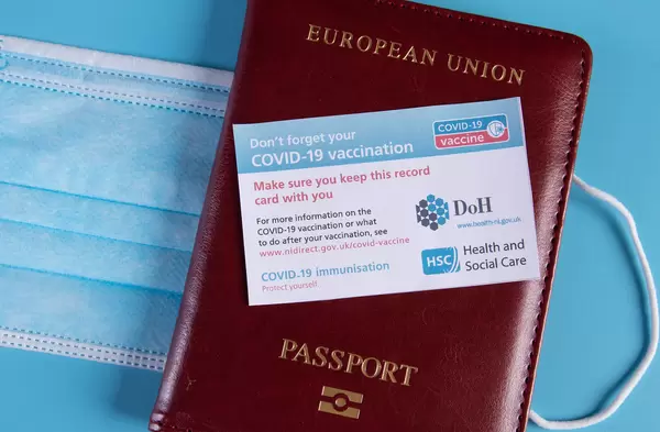 Covid-19 vaccination record card with passport on blue background