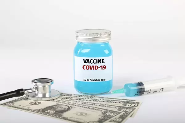 Covid-19 vaccine with money, stethoscope and syringe on white background