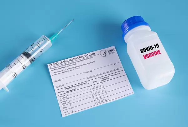 Covid-19 vaccine with syringe and vaccination record card