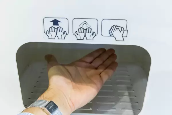 Covid and travel: close-up of man's hand placed under contactless disinfection device at BER airport