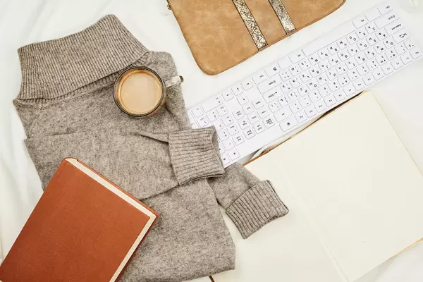 Cozy workspace at home with keyboard, book and cup of coffee