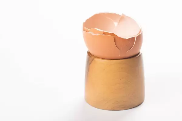 Crashed Eggshell on the wooden holder isolated above white background