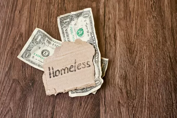 Creasy one-dollar bills and homeless note on torn paper