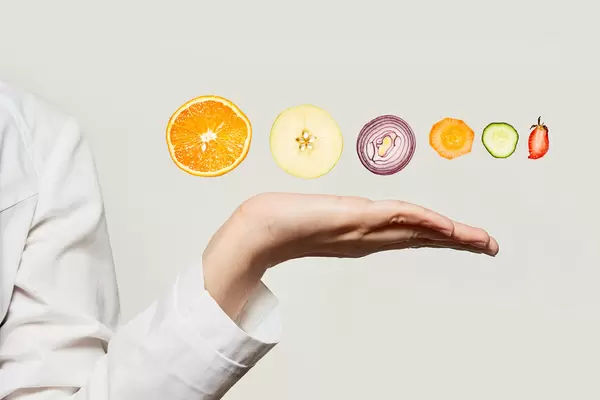 Creative concept of healthy dieting - nutritionist doctor hand holding vegetables and fruits slices