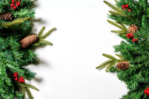 Creative frame made of Christmas fir branches on white background with red decoration and pine cones