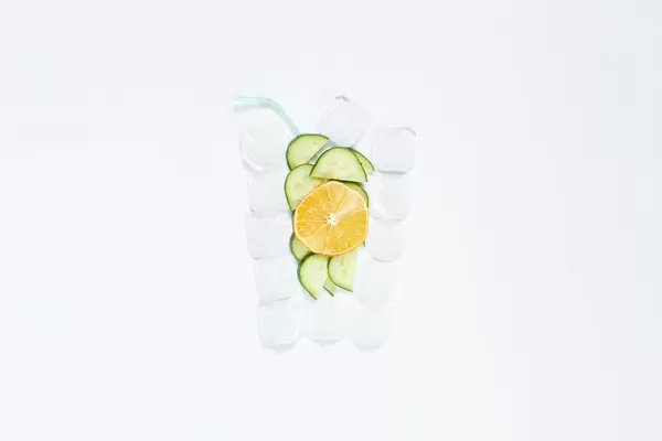 Creative summer drink shape made of ice cubes, cucumber and lemon slices