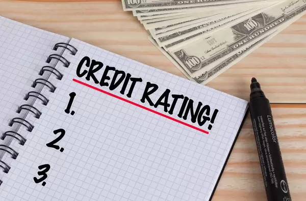 Credit Rating text in notebook and Dollar banknotes on wooden table