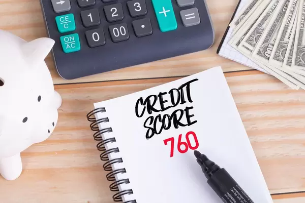 Credit score 760 text in notebook with piggy bank and calculator on wooden table