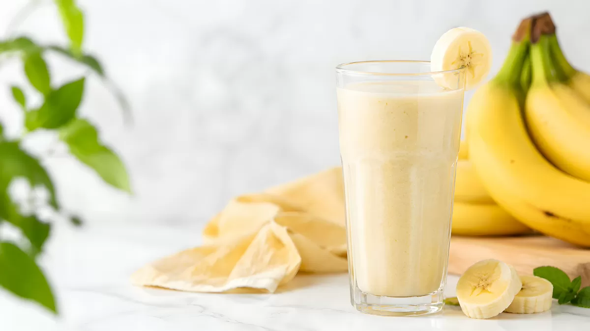 Cremiger Bananensmoothie im Glas mit frischen Bananen