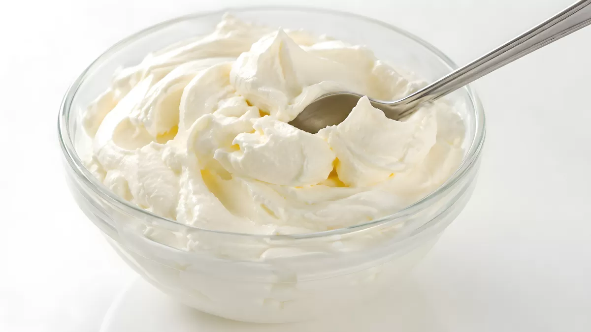 Cremiger Frischkäse in Glasschüssel mit Löffel