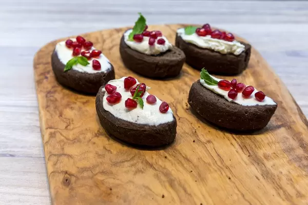 Cretan carob rusks with cream and pomegranate seeds on a wooden board