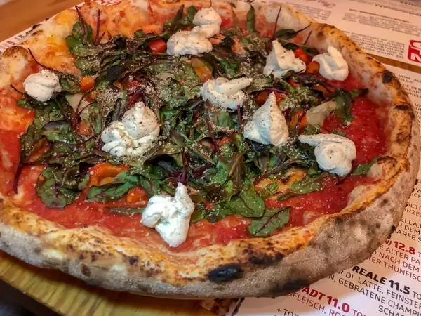 Crispy pizza with fresh basil and unmelted mozzarella cheese on pizzeria table