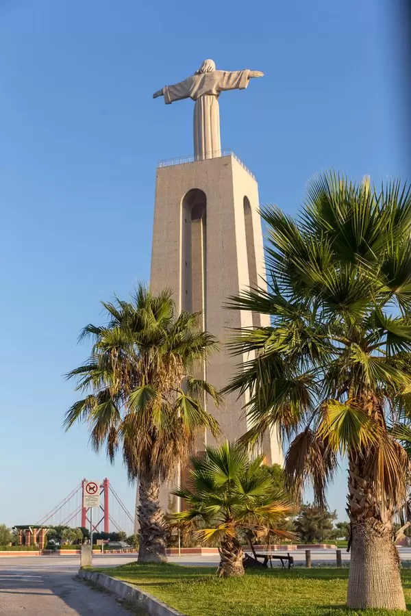Cristo Rei Statue von hinten mit Palmen in Almada Lissabon