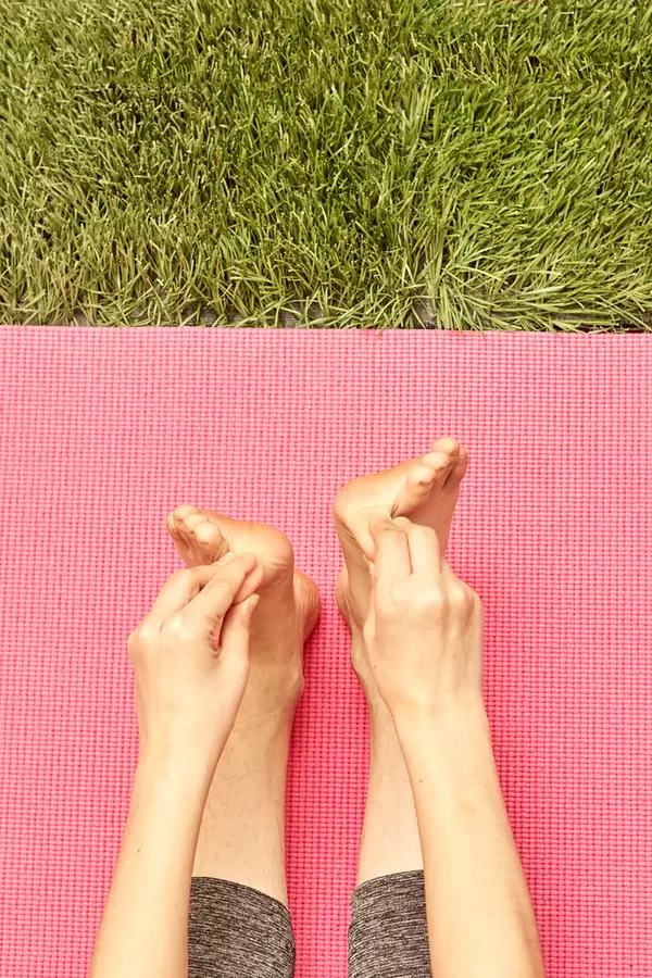 Cropped shot of a young lady doing warming exercises - stretching foot fingers