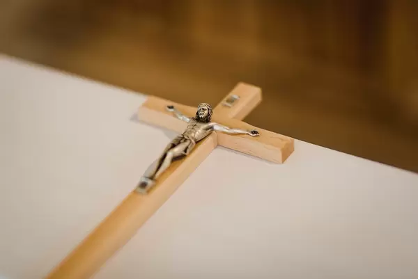 Cross Laying Flat On White Surface With Golden Body Of Jesus Christ