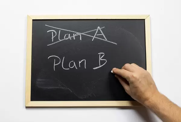 Crossing out Plan A and writing Plan B on a blackboard