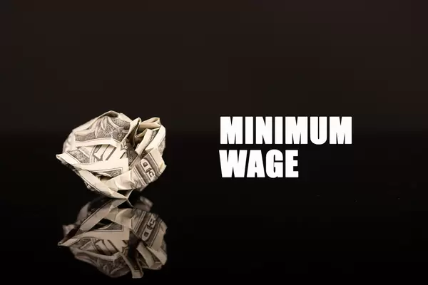 Crumpled money with Minimum wage text