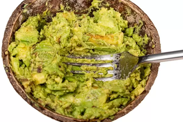 Crushed avocado in a bowl with a fork