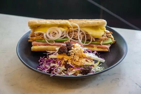 Cuban Sandwich on a French Baguette with Pulled Pork, Melted Swiss Cheese, Ham and other Ingredients with Coleslaw Salad on Side
