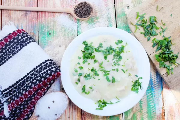 Cullama mit Hähnchen und Pilzen: Gericht aus der Türkei in einem weißen Teller auf hölzernem Hintergrund