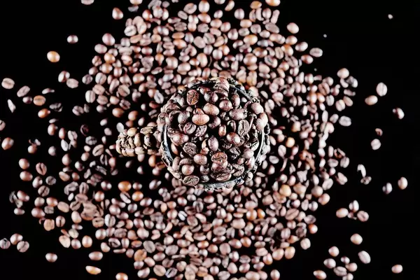 Cup full of coffee beans, black background