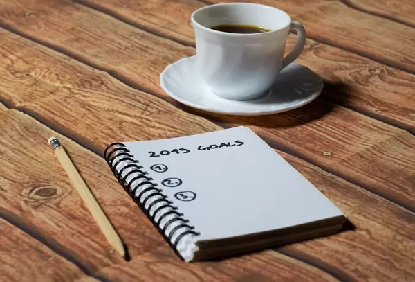 Cup of coffee and notebook on office wood table