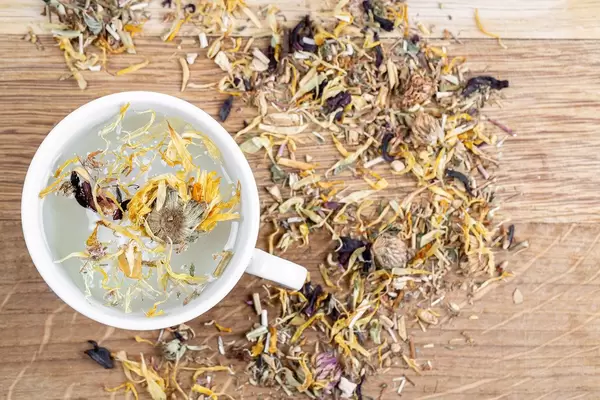 Cup of fresh green tea with different flower petals, top view