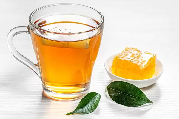 Cup of hot tea with green leaves and honeycomb