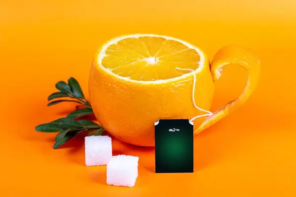 Cup of tea in the form of orange on orange background