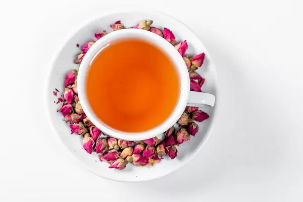 Cup of tea surrounded by dry rose buds