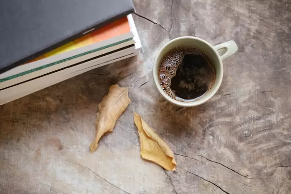 Cup of warm dark coffe and books on a rustic table