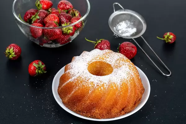 Cupcake with icing sugar and strawberries on a black background