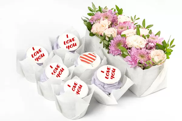 Cupcakes and bouquet of flowers on white background, concept of congratulations on valentine's day, mother's day or women's day